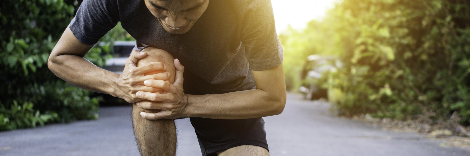 An injured sportsman with knee pain touching the painful knee area.