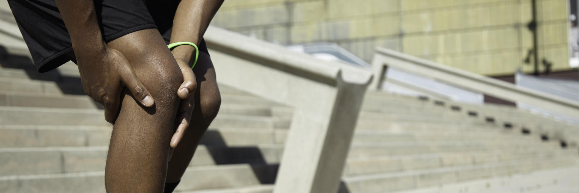 An Afro-American sportsman stopped by knee pain while he was running down the stairs.