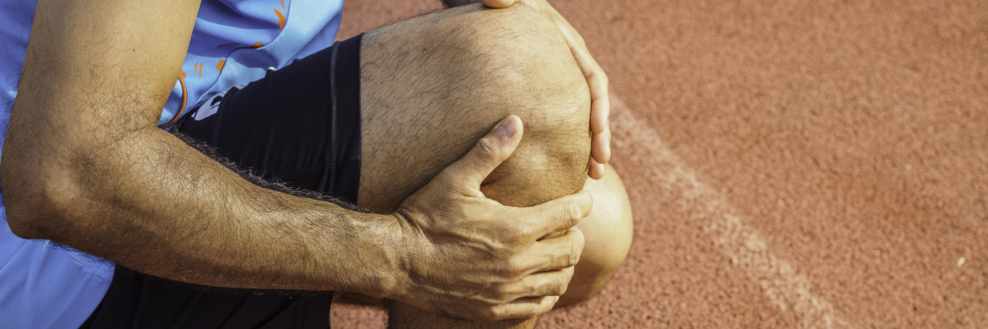 An athlete with knee pain touching the painful knee area.