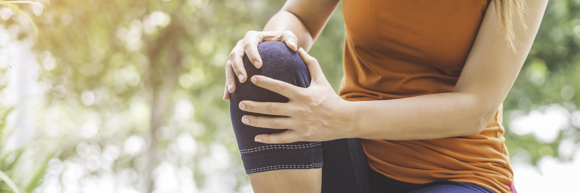 A woman with knee pain touching the painful knee.