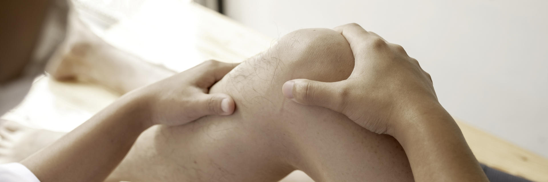 A physician examining patient's knee joint.