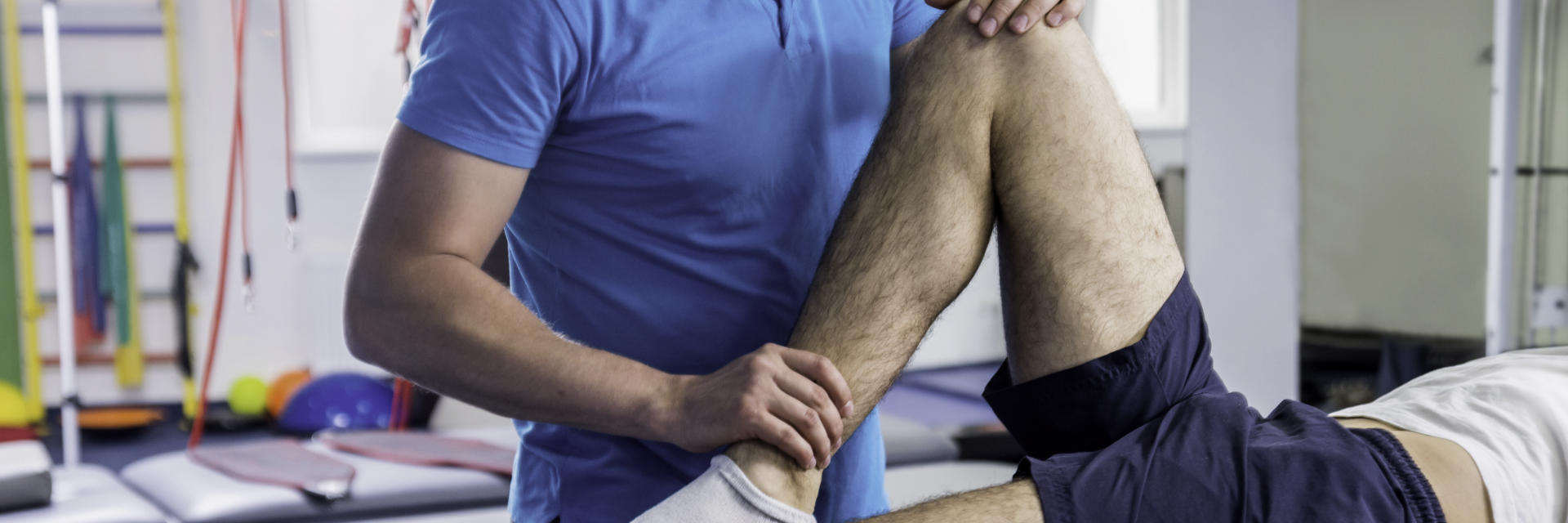 A physiotherapist examining patient's knee joint.