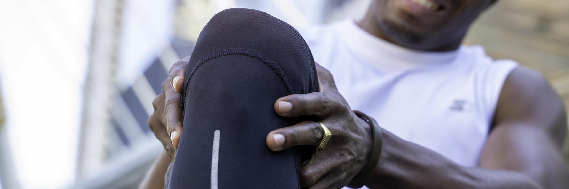 An Afro-American sportsman in pain touching the painful knee area.