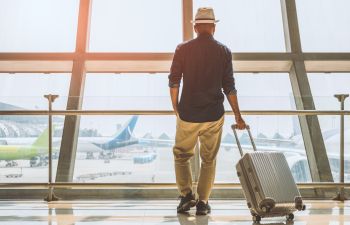 A man with a trolley suitcase at an airport.